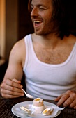 Mann im Unterhemd isst Frühstücksei
