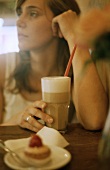 Woman with a glass of milky coffee in café