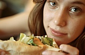 Young woman with open sandwich (on flatbread)