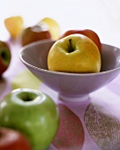 Fresh apples, two in purple bowl