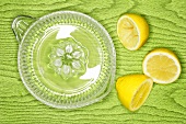 Lemons on lemon squeezer on green wooden background