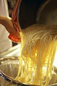 Noodles being poured out of the pan into a strainer