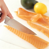 Lachsfilet wird mit Messer geschnitten (für Sushi)