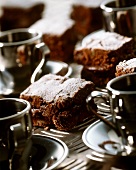 Schokoladenkuchen in Schnitten und Kaffeetassen