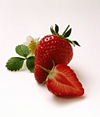 One half and one whole strawberry & strawberry flower