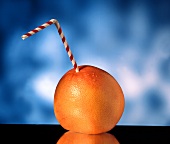 A grapefruit with a straw