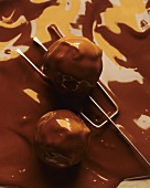 Dipping marzipan balls into chocolate (close-up)