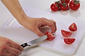 Cutting the flesh out of quartered tomatoes