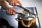 Spätzle zubereiten: Teig ins kochende Wasser pressen