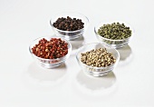 Various peppercorns in glass bowls