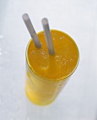 Mango drink with ice cubes and drinking straws