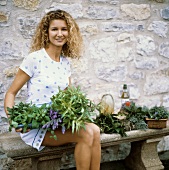 Young woman sitting on a bench with fresh herbs