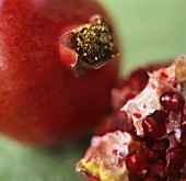 Whole and cut pomegranate on a green background