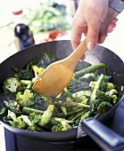 Green vegetables in a pan with wooden spoon