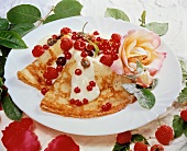 Pancakes with berries, vanilla sauce and candied roses