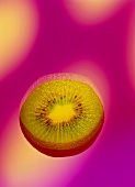 Eine Kiwischeibe vor pinkfarbenem Hintergrund (verfremdet)