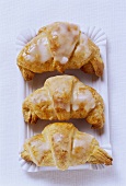 Croissants with glacé icing on paper plate 