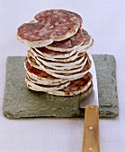 Farmhouse salami, sliced, on flat stone