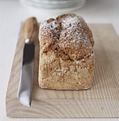 Wholemeal bread on chopping board with bread knife