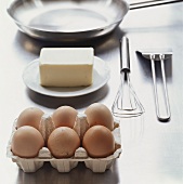 Eggs, butter, whisk, frying pan (ingredients for omelette)