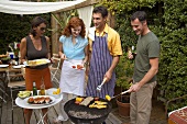 Two couples barbecuing food in garden