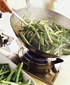 Frying green beans and spring onion in a wok
