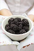 Woman holding bowl of blackberries