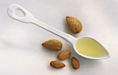 Almond oil on spoon, surrounded by almonds