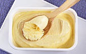 Margarine in tub and on wooden spoon