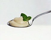 A spoonful of mayonnaise with herb leaves