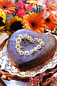 Herzförmiger Schokoladenkuchen mit Gänseblümchen