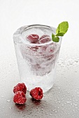 Eisglas mit klarem Schnaps und Himbeeren