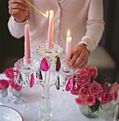 Woman lighting candles on table laid for special occasion