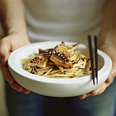 Person serving noodles with grilled squid