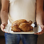 Man serving roast chicken on a platter