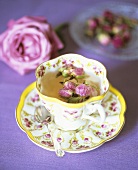 Tee mit Rosenknospen in romantischer Tasse
