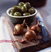 Shallots and green olives on chopping board