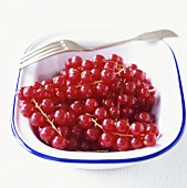 Redcurrants in a dish with a fork