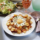 Fried potatoes with fried egg and salad