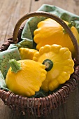 Several yellow patty pan squashes in a basket