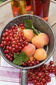 Redcurrants & apricots in pan in front of bottles of juice