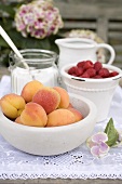 Apricots and raspberries in bowls on garden table