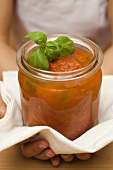 Hands holding jar of home-made tomato sauce