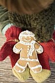 Child's hands in woollen mittens holding gingerbread man