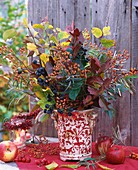 Vase of rose hips, sloes and autumn leaves