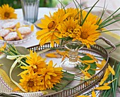 Bunches of heliopsis and grasses on tray and in glass