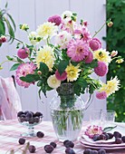 Blumenstrauss aus weissen und rosa Dahlien, daneben Pflaumen