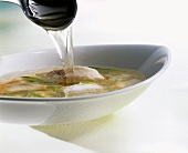 Pouring fish soup with sole into plate