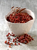 Red peppercorns in and beside bowl