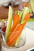 Raw carrots and cucumber sticks in a glass